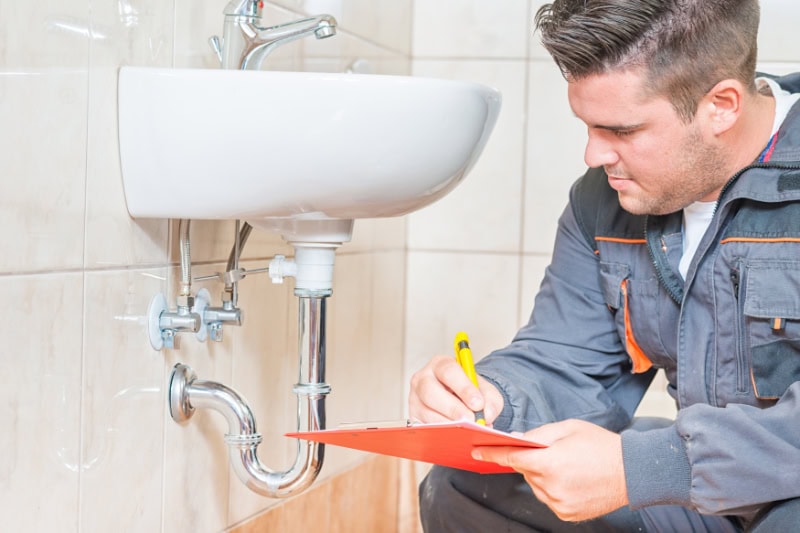 Do I Need a Plumbing Inspection? Photo of a plumber performing maintenance on a bathroom sink.