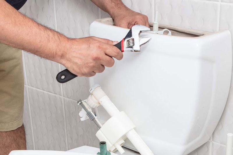 How to Unclog Your Slow-Draining Toilet in Springbank. A plumber doing some repairs on a toilet.