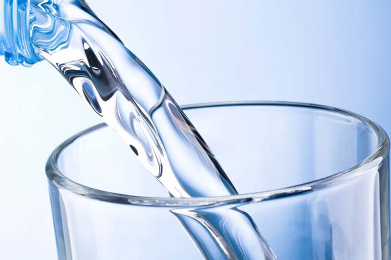 All About Water Softeners Problems—and How to Fix Them. Close up photo of drinking water being poured into a glass.